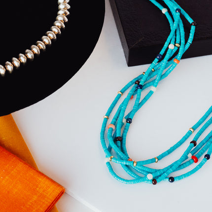 Product shot of two necklaces. One is a beaded turquoise necklace and the other is sterling silver balls