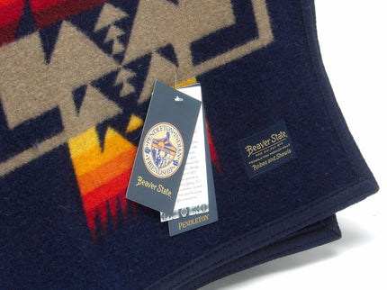 Pendleton Chief Joseph Blanket in indigo featuring a traditional Native American-inspired geometric pattern with arrow motifs, folded neatly to show intricate design and soft wool texture. Tag View 