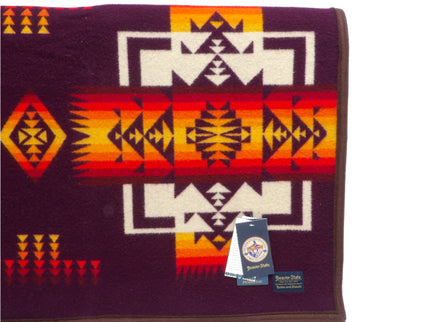 Pendleton Chief Joseph Blanket in Maroon featuring a traditional Native American-inspired geometric pattern with arrow motifs, folded neatly to show intricate design and soft wool texture. Front view