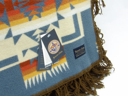 Pendleton Chief Joseph Blanket in Shale featuring a traditional Native American-inspired geometric pattern with arrow motifs, folded neatly to show intricate design and soft wool texture, Tag view