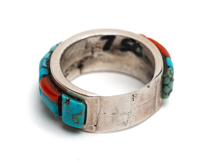Bottom of silver ring with turquoise and coral inlay on a white background