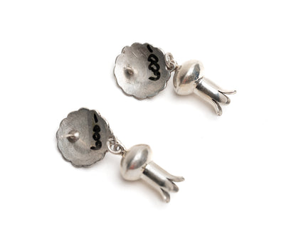 Pair of circular silver earrings with dangling silver shaped like flower stems a white background
