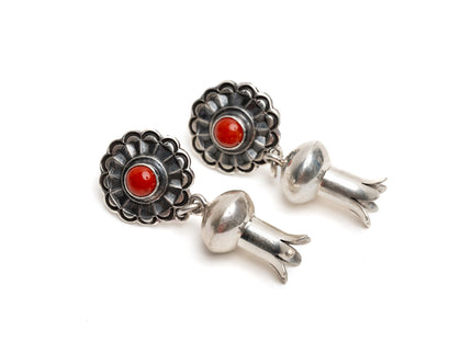 Pair of silver earrings with a single coral stone in the center of silver shaped like a blossom on a white background