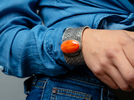 Woman's hand wearing a silver bracelet with an orange gemstone