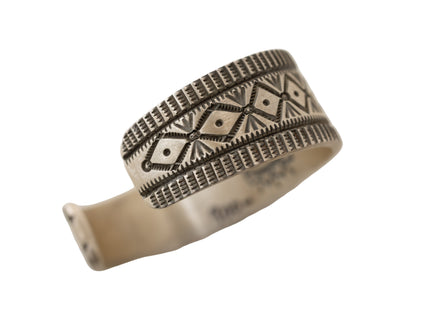 Silver ring with intricate stamped patterns on a light white background