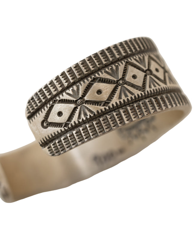 Silver ring with intricate stamped patterns on a light white background