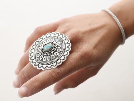 Native American sterling silver ring with a turquoise stone on a hand against a white background