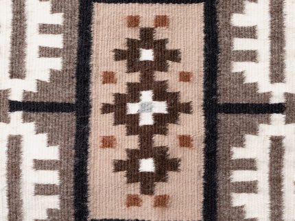 Close up of a Navajo handwoven rug with geometric pattern featuring brown, beige, and white colors.