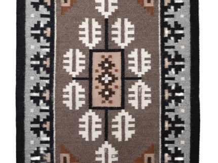 Traditional Navajo handwoven rug with a brown center and a grey and black borden featuring a Navajo geometric patterns