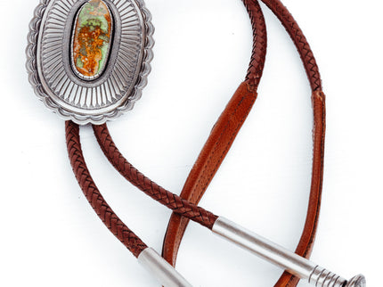 A Sterling Silver Bolo Tie with a Brown Leather Strap, featuring a central emerald-colored stone and two silver tips.