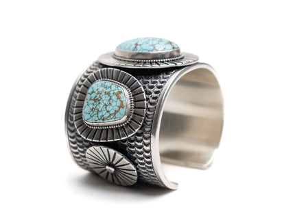 Native American silver cuff bracelet with 3 number eight turquoise stones on a white background