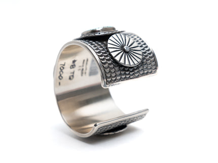Silver cuff bracelet with textured design on a white background