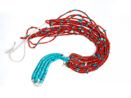 Top view of single Native American necklace with nine strands of Mediterranean coral with sleeping beauty, Royston and Kingman Turquoise stones, and Lapis on a white background