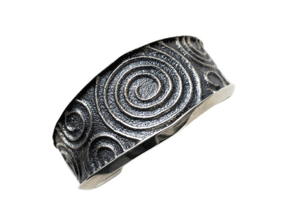 Silver cuff bracelet with spiral pattern on a white background