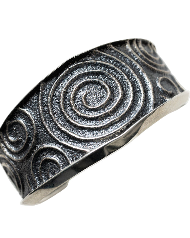 Silver cuff bracelet with spiral pattern on a white background