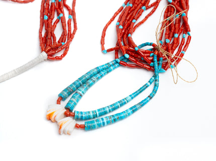 Turquoise and coral beaded necklace on a white background