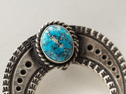 Sonaron Gold turquoise stone on a Silver u-shaped jewelry pieceon a light gray background