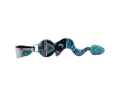 Side view of a pendant shaped like a snake made with turquoise, jet black stone, and sterling silver with a moon in the middle and a circular head with the design of a Navajo deity