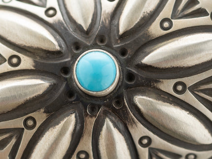 Close up of a Sleeping Beauty turquoise gemstone and hand-stamped pattered around it
