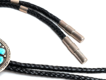 Black leather braided cord with silver and turquoise bolo tie on a white background