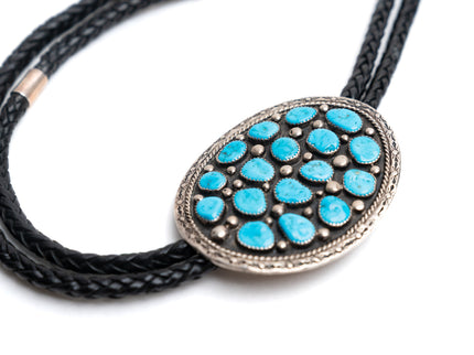 Bolo tie with 17 turquoise stones and black cord on a white background