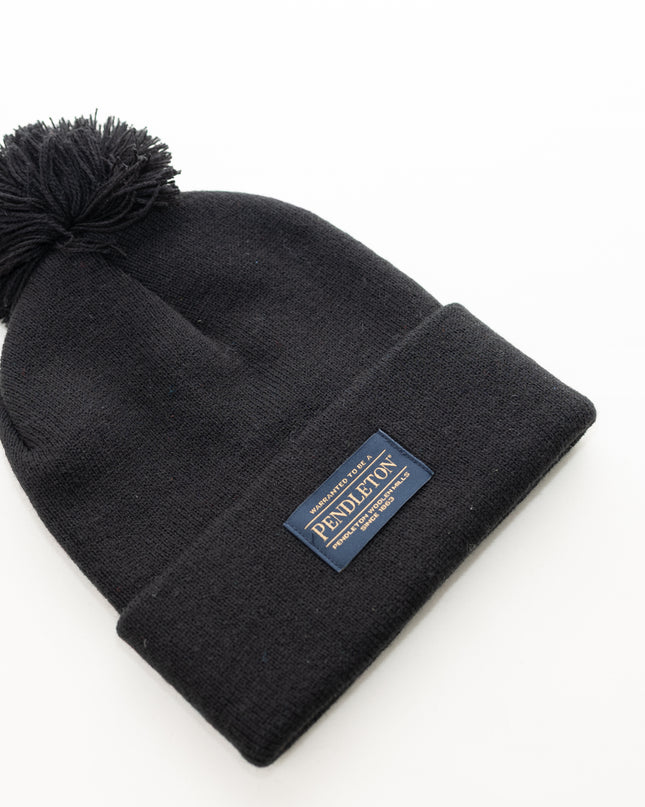Flat view of a Pendleton classic black beanie with pom-pom and logo on a white background