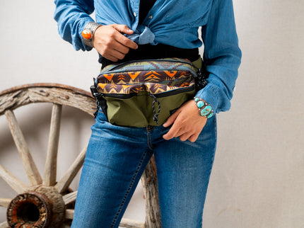 Person wearing a Pendleton patterned waist bag with a rustic wheel in the background