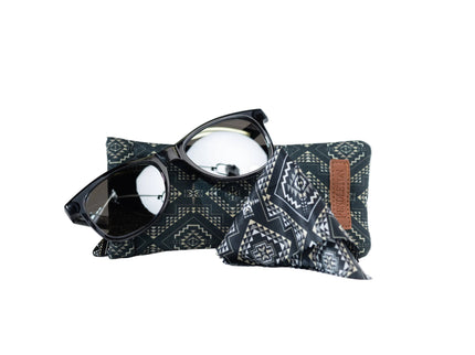 Sunglasses on a patterned pouch with a brown patch on a white background