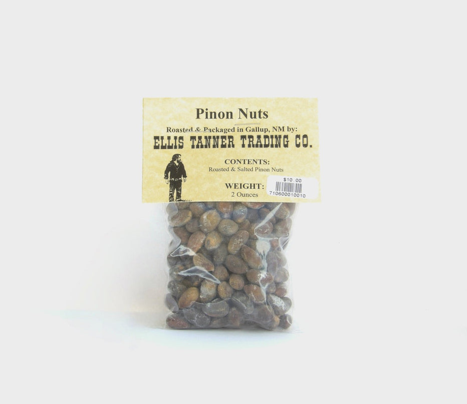 A clear plastic package containing roasted pinon nuts, with a label displaying the brand name, product name, and weight.