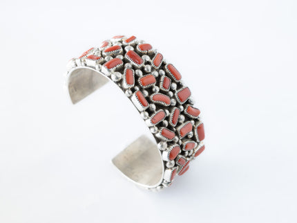 Navajo sterling silver, coral cluster bracelet on top of a white background.