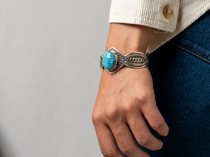Hand wearing a silver Terry Martinez bracelet with a turquoise stone against a neutral background