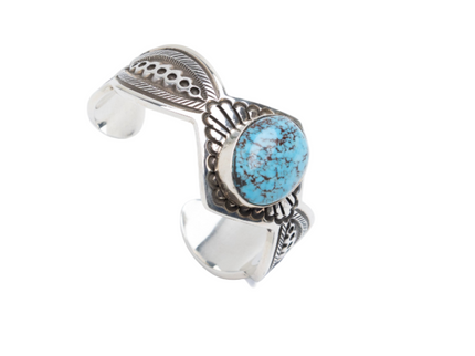 Silver bracelet with deep black lines and a turquoise stone on a white background