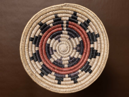 Vintage hand-woven basket with concentric circle pattern on a brown background