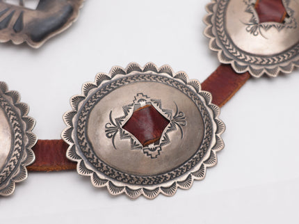Close-up of a conch belt with stamped silver conchos on a white background