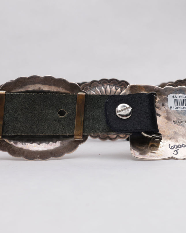 Silver belt buckle with black strap on a white background