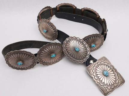 Black leather concho belt with silver concho buckles on a white background