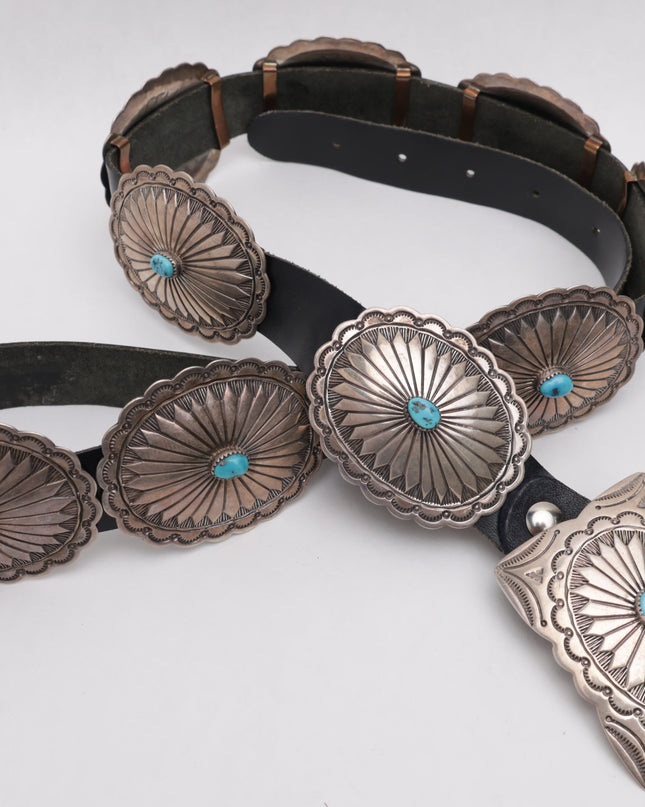 Black leather concho belt with silver concho buckles on a white background