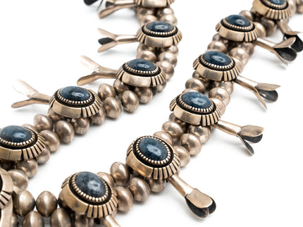 A close-up image of a vintage squash blossom necklace with lapis stones and metal accents, displaying the detailed craftsmanship and the vibrant blue color of the lapis.