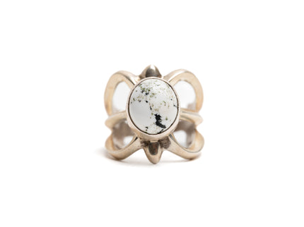 Silver cast cut-out ring showcases a single, centrally set round white buffalo stone. Ring appears gold because of the natural patina