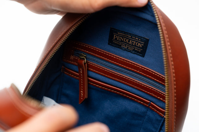 Close-up of a Pendleton leather bag with open zipper showing blue interior.