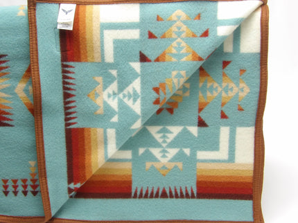 Pendleton Chief Joseph Blanket in aqua, featuring a traditional Native American-inspired geometric pattern with arrow motifs, folded neatly to show intricate design and soft wool texture