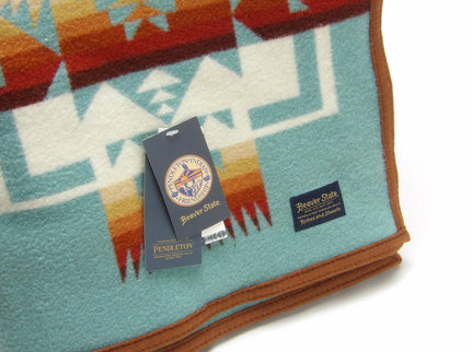 Pendleton Chief Joseph Blanket in aqua, featuring a traditional Native American-inspired geometric pattern with arrow motifs, folded neatly to show intricate design and soft wool texture