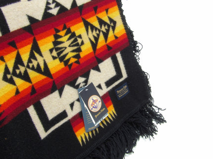 Pendleton Chief Joseph Blanket in Black featuring a traditional Native American-inspired geometric pattern with arrow motifs, folded neatly to show intricate design and soft wool texture. tag view