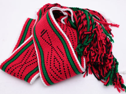 Dark red traditional sash with two green lines and black and white highlights rolled up on a white background