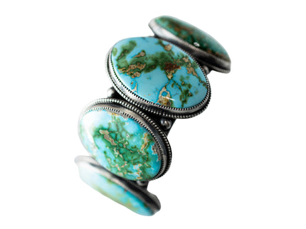 Circular Turquoise stone cuff with silver band on a light gray background