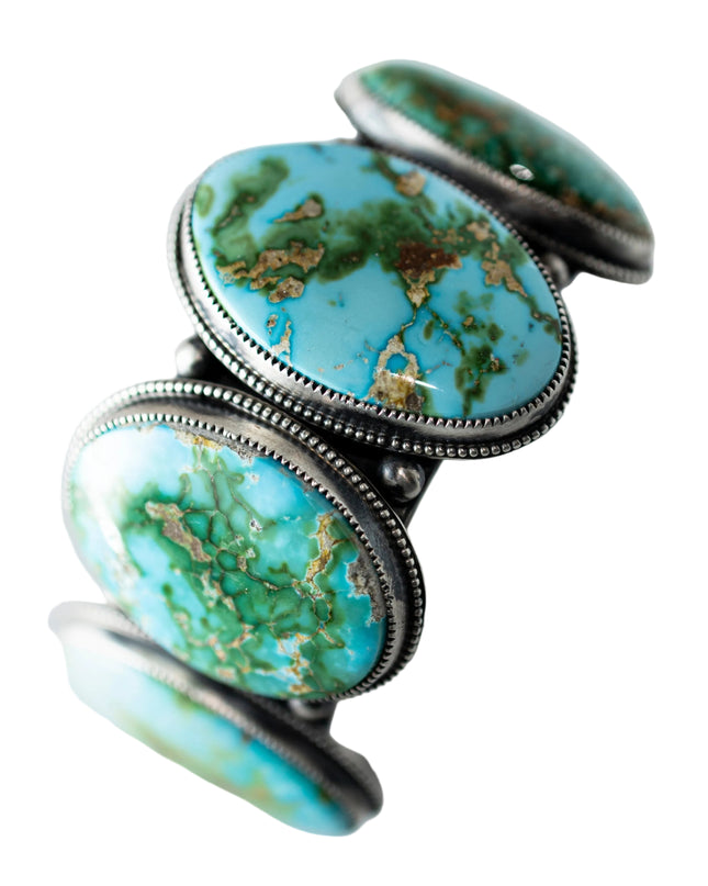 Circular Turquoise stone cuff with silver band on a light gray background