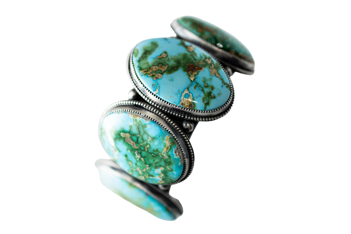 Circular Turquoise stone cuff with silver band on a light gray background