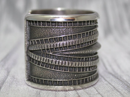 Large Sand Cast Cuff. Crafted from sterling silver using the sand cast technique, this cuff features unique texture and shine, on a shiny silver cloth.