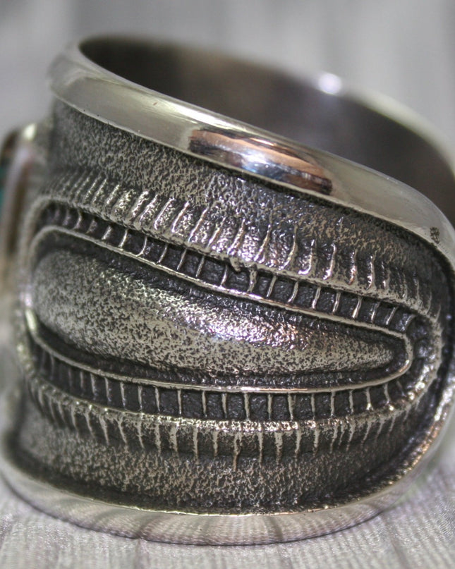 A bold sand-cast cuff featuring intricate textures and patterns, Side Profile. 
The design reflects a balance of rugged craftsmanship and refined artistry.