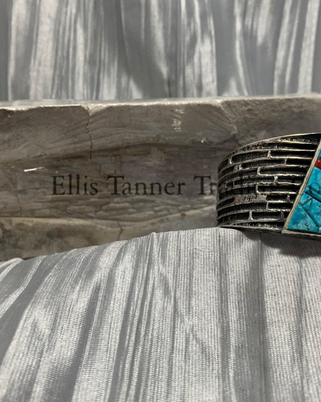 Displayed is a silver tufa cobbletone bracelet, on a silver shiny sheet 